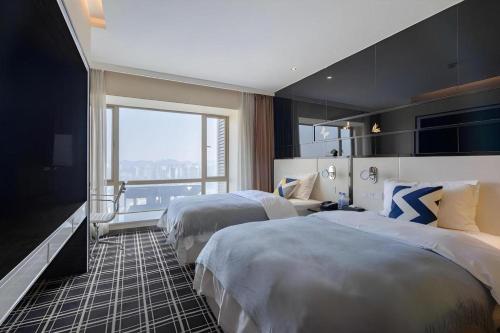 a hotel room with two beds and a large window at GreenTree Alliance Hotel Guiyang Huaguo Community Central Business Zone in Guiyang