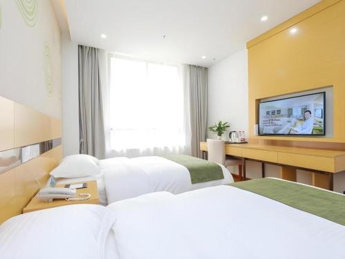 a hotel room with two beds and a flat screen tv at GreenTree Inn Jiaxin Puyuan Kaixuan Road in Jiaxing