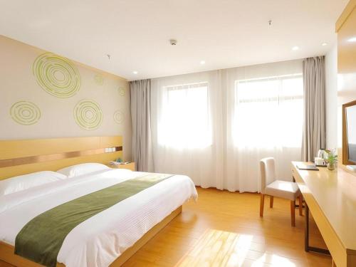 a bedroom with a large bed and a desk and window at GreenTree Inn Jiaxin Puyuan Kaixuan Road in Jiaxing