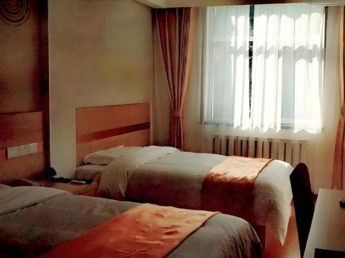 a hotel room with two beds and a window at GreenTree Inn Langfang GuAn County Xinyuan Street Express Hotel in Langfang
