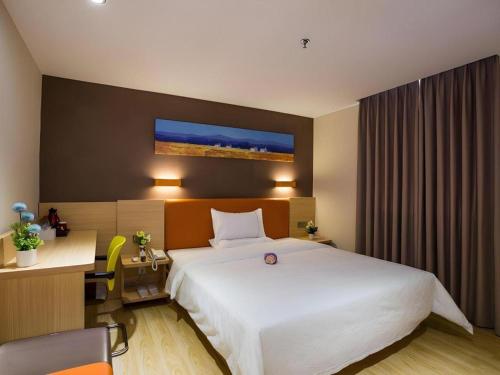 a hotel room with a large white bed and a desk at IU Hotel Chengdu High-Tech Zone Longhu Times Street in Chengdu