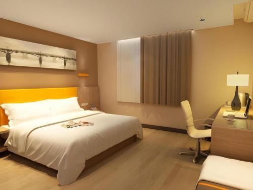 a hotel room with a bed and a desk and a chair at IU Hotel Chengdu High-Tech Zone Longhu Times Street in Chengdu