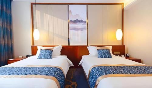 a hotel room with two beds with blue pillows at YUN-RAY Hotel Shijiazhuang in Shijiazhuang