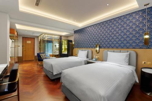 a hotel room with two beds and a blue wall at OKU Hotel in Taichung