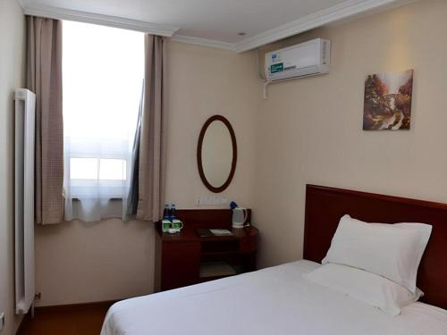a bedroom with a bed and a mirror and a window at GreenTree Inn Beijing Shangdi East Anningzhuang Road Shell Hotel in Beijing