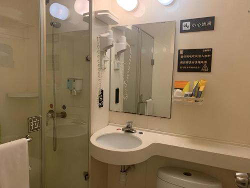 a bathroom with a sink and a mirror and a toilet at 7 Days Inn Qingdao Liaoyang West Road Xinye Plaza Metro Station in Qingdao