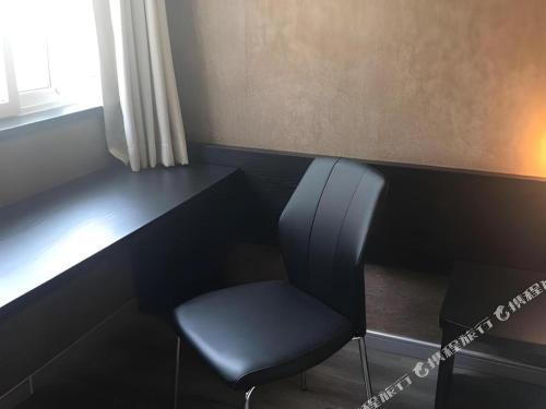 a black desk with a chair next to a window at 7 Days Inn Qingdao Liaoyang West Road Xinye Plaza Metro Station in Qingdao