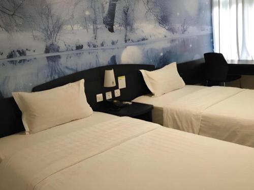 a hotel room with two beds with white pillows at 7 Days Inn Qingdao Liaoyang West Road Xinye Plaza Metro Station in Qingdao