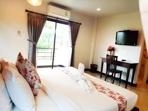 a bedroom with a large white bed with a window at Rittiboon Vintage Hotel in Phrae