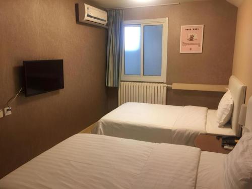 a hotel room with two beds and a television at 7 Days Inn Qingdao Liaoyang West Road Xinye Plaza Metro Station in Qingdao
