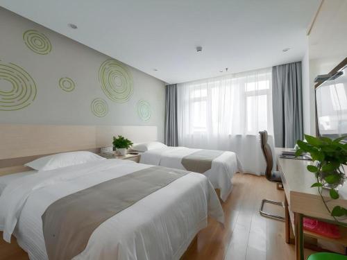 a hotel room with three beds and a window at GreenTree Inn Wuhu Eshan Road University City in Wuhu
