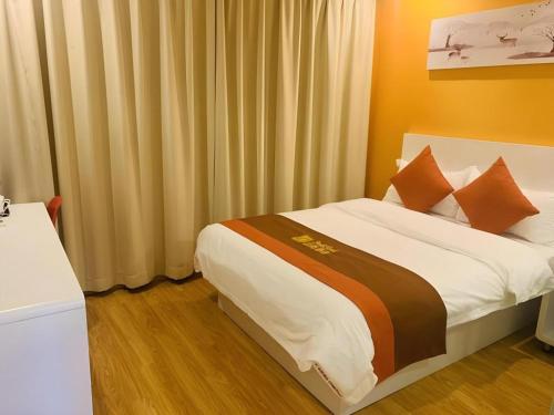 a bedroom with a bed with orange walls and curtains at Shell Shanghai Songjiang District Xinqiao Town Xinqiao Hotel in Chunshen