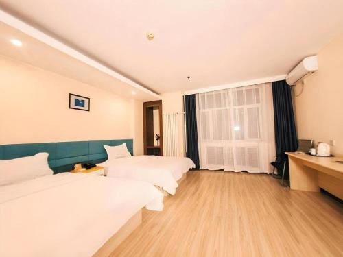 a hotel room with two beds and a desk at 7 Days Inn Harbin Medical University First Affiliated Hospital in Harbin