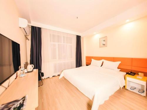 a hotel room with a white bed and a television at 7 Days Inn Harbin Medical University First Affiliated Hospital in Harbin