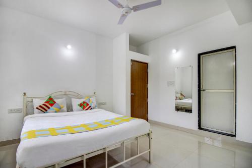 a white bedroom with a bed and a mirror at Hotel O Muktesh Chandra in Goa