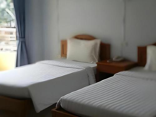 two twin beds in a room with a window at Ritzy House Hotel in Chumphon