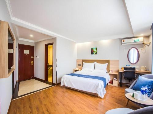a bedroom with a bed and a desk and a chair at GreenTree Inn Jiaxing Tongxiang Tudian Express Hotel in Jiaxing