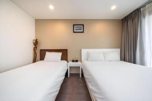 two beds sitting next to each other in a room at Sea View Hotel in Jeju