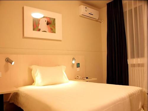 a bedroom with a bed and a picture of a dog at Jinjiang Inn Dalian Development Zone Jinma Road Light Railway Station in Jinzhou