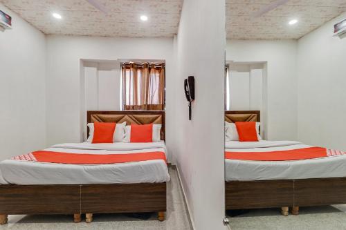 two beds in a room with white walls and orange pillows at Hotel O Sun View in Ludhiana