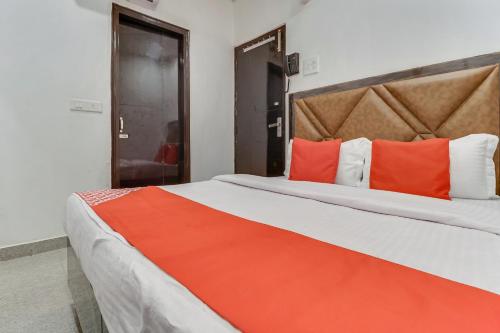 a bedroom with a large bed with orange pillows at Hotel O Sun View in Ludhiana