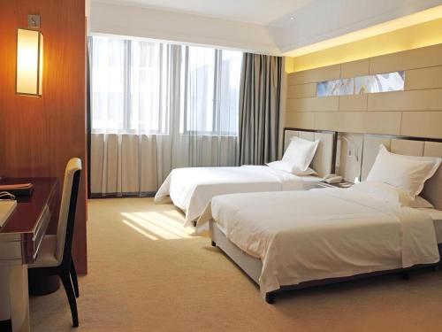 a hotel room with two beds and a desk at Nanning Prince Hotel in Nanning