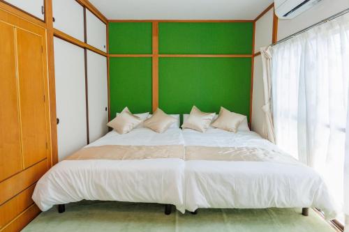 a bedroom with a large bed with a green wall at tsuki-funado in Tokyo