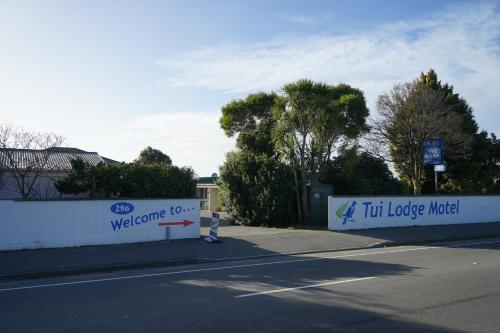 a sign that reads welcome to tu long motel next to a street at Tui Lodge Motel in Christchurch