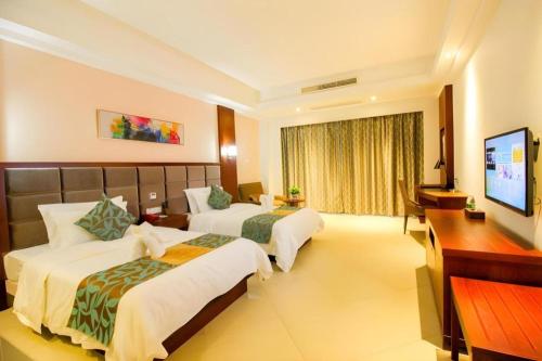 a hotel room with two beds and a television at Qionghai Jin Mao Hotel in Qionghai