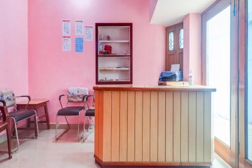 a salon with pink walls and a counter with chairs at Hotel O Shivaye Rest House in Deoghar