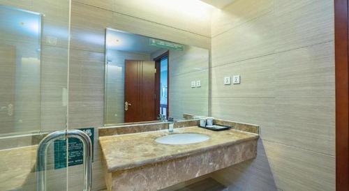 a bathroom with a sink and a large mirror at GreenTree Inn Taiyuan PinGYAng Road Business Hotel in Taiyuan