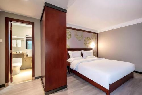 a bedroom with a large white bed and a bathroom at GreenTree Inn Nanning Langdong Hotel in Nanning
