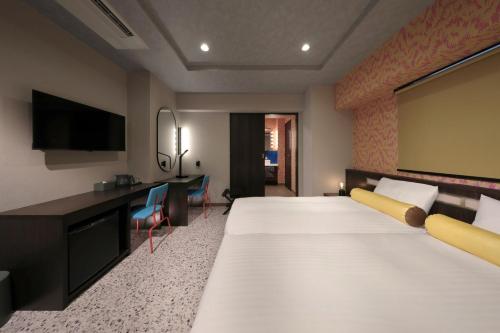 a hotel room with a large bed and a flat screen tv at Nipponbashi Luxe Hotel in Osaka