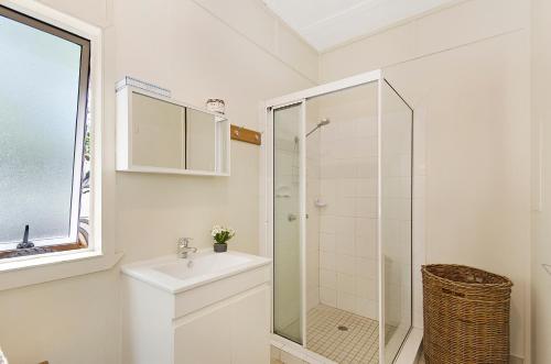 bagno bianco con doccia e lavandino di Strand Motel a Townsville