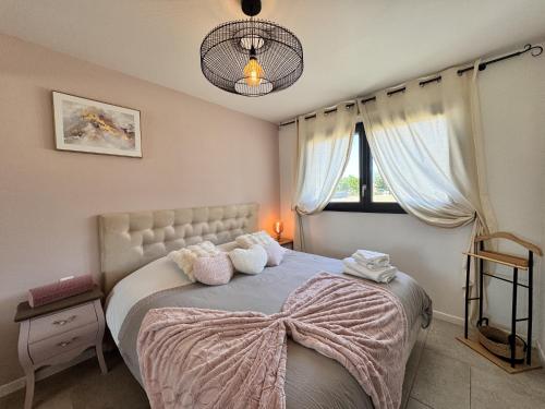 Un dormitorio con una cama con almohadas y una ventana. en La Bella Rosa - Direct circuit - Piscine - Climatisation, en Le Mans