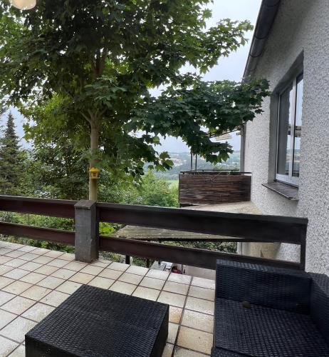 a patio with two chairs and a tree and a fence at Fuldablick Melsungen 1 in Melsungen