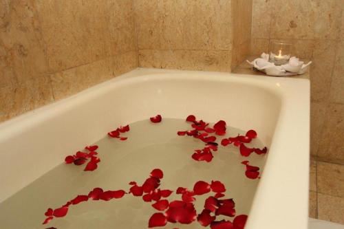 a bath tub filled with red flower petals at Hotel Horison Arcadia Heritage Surabaya in Surabaya