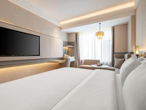 a hotel room with a bed and a flat screen tv at Tianrun International Hotel in Dunhuang