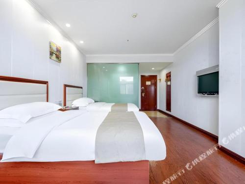 a bedroom with a large white bed and a flat screen tv at GreenTree Inn Yinchuan Pedestrian Street East Liqun Street Express Hotel in Yinchuan