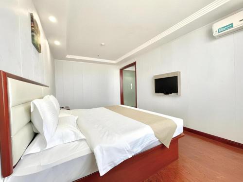 a bedroom with a white bed and a television at GreenTree Inn Yinchuan Pedestrian Street East Liqun Street Express Hotel in Yinchuan