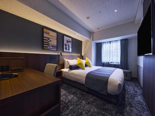 a hotel room with a bed and a desk at Hotel Villa Fontaine Kobe Sannomiya in Kobe