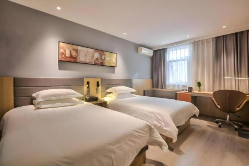 a hotel room with two beds and a desk at Jinjiang Inn Taizhou Huangyan Jiufeng Park in Daidong