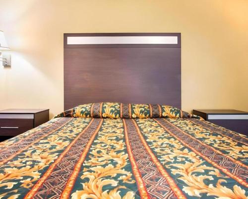 a bedroom with a large bed with a wooden headboard at Rodeway Inn Mount Laurel Hwy 73 in Mount Laurel