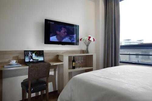 a bedroom with a bed and a tv on a wall at Hanyong Hotel Shenzhen International Exhibition Center in Shenzhen