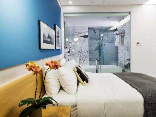 a bedroom with a white bed and a blue wall at Hotel Denim Seoul in Seoul