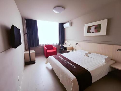a hotel room with a large bed and a red chair at Jinjiang Inn Handan Zhonghua Nan Street Xueyuan Bei Road in Handan