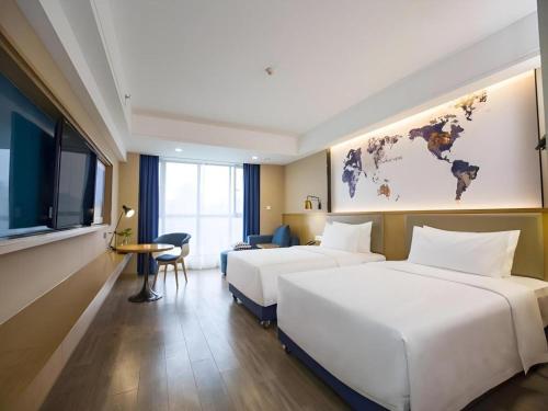 two beds in a hotel room with a map of the world at Kyriad Marvelous Hotel·Xi'an North High-speed Railway Station in Xi'an