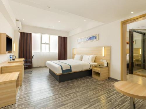 a hotel room with a bed and a desk at City Comfort Inn Zhaoqing Qixingyan Scenic Area Xinghu Archway in Zhaoqing