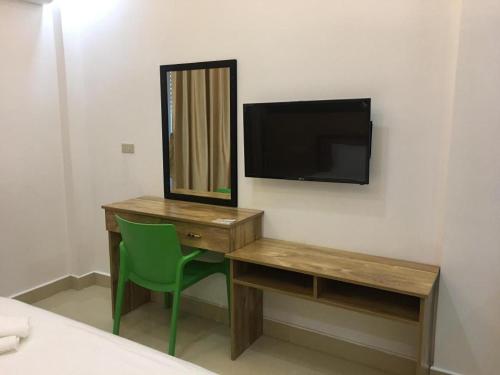 a room with a desk and a television and a green chair at Hotel Primera in Zamboanga
