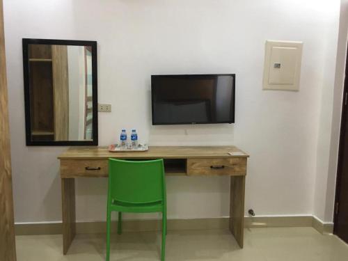 a desk with a television and a green chair at Hotel Primera in Zamboanga